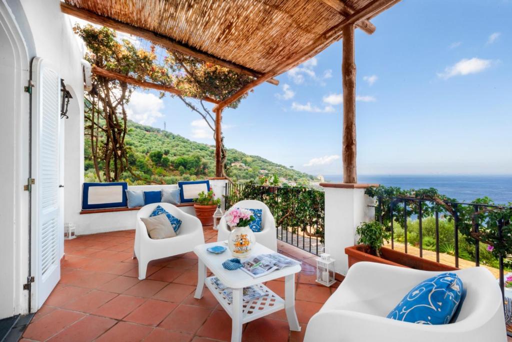 Elle comprend une terrasse dotée d'un mobilier blanc et offrant une vue sur l'océan. dans l'établissement YourHome - Villa Mia, à Massa Lubrense