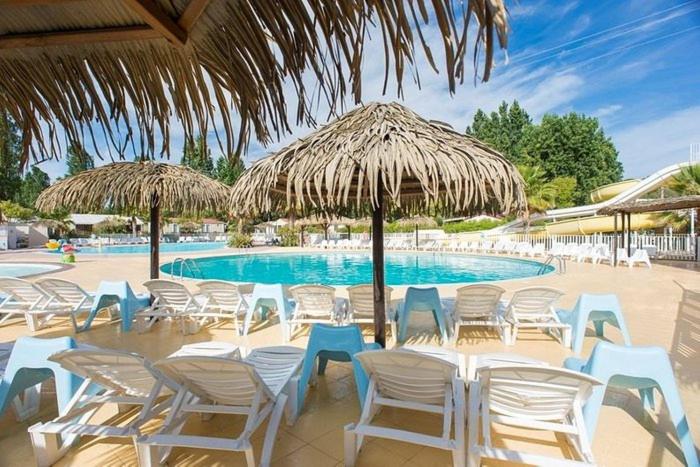 un groupe de chaises et de parasols à côté d'une piscine dans l'établissement Mobile home exotique de 40 m2, à Fréjus