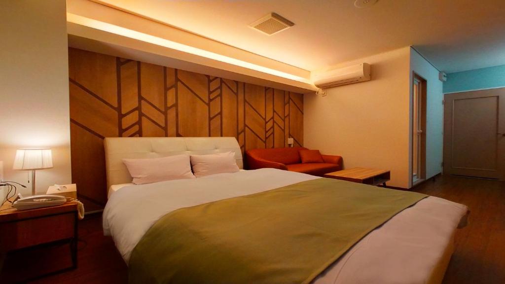 une chambre d'hôtel avec un grand lit et une chaise dans l'établissement Hotel Wave大人専用, à Hiroshima