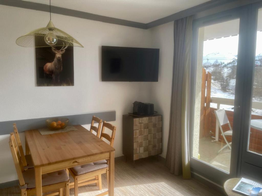 une salle à manger avec une table en bois et une télévision dans l'établissement Pierre et Vacances Les Bergers - Piscine Sauna, à L'Alpe-d'Huez