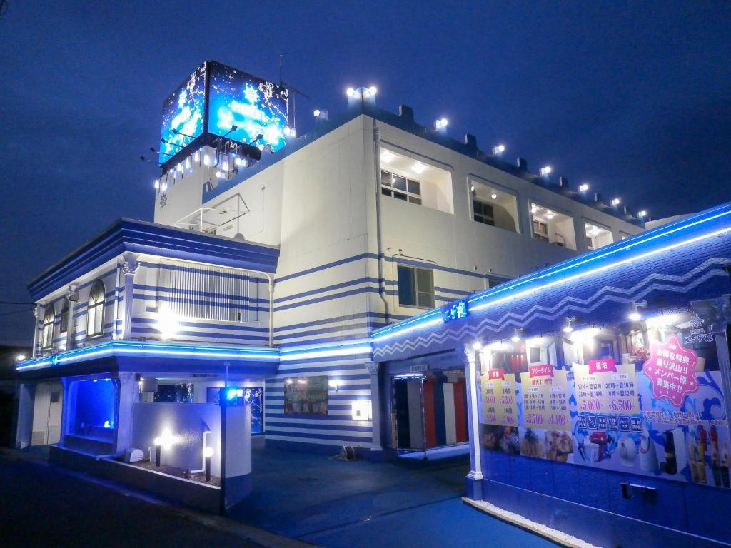 Un bâtiment blanc avec des lumières bleues devant lui dans l'établissement ホテルエーゲ海 - ラブホテル, à Shizuoka
