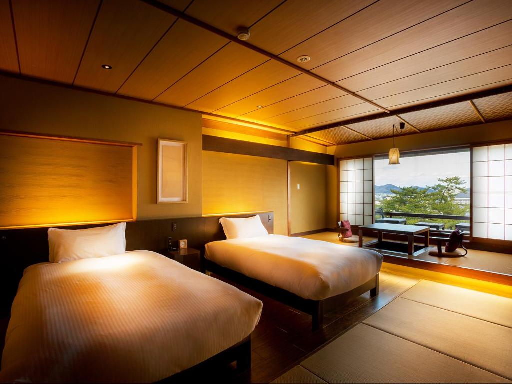 une chambre d'hôtel avec deux lits et une fenêtre dans l'établissement Kotohira Kadan, à Kotohira