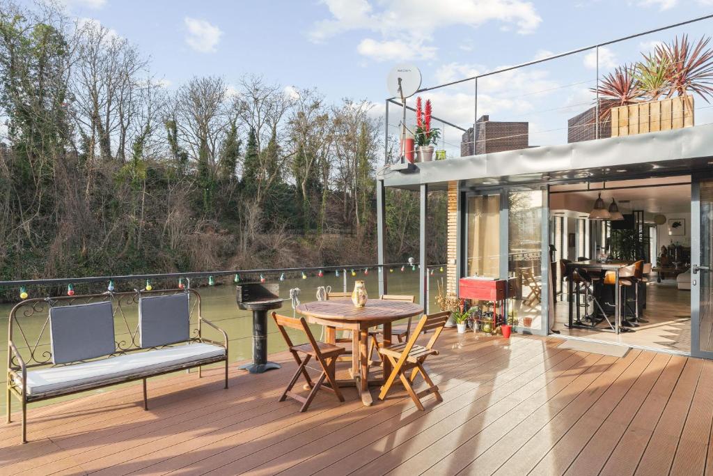 un patio avec une table et des chaises sur une terrasse dans l'établissement Péniche, à Issy-les-Moulineaux