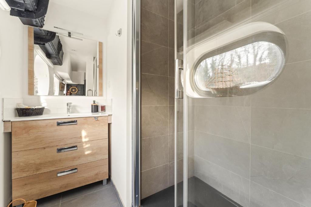 une salle de bain avec une douche, un lavabo et un miroir dans l'établissement Péniche, à Issy-les-Moulineaux 8 autres photos