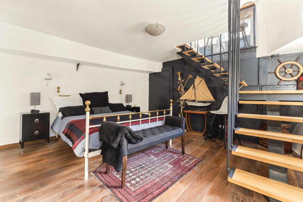 une chambre avec un lit et un escalier en colimaçon dans l'établissement Péniche, à Issy-les-Moulineaux