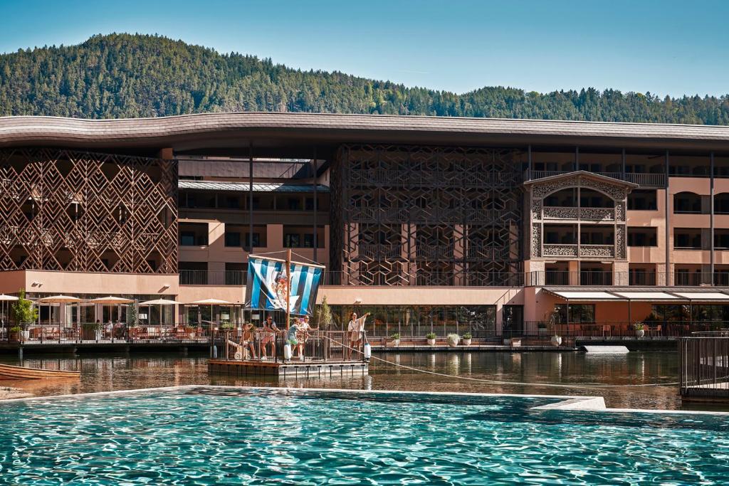 un hôtel avec une piscine devant un bâtiment dans l'établissement Falkensteiner Family Resort Lido Superior, à Chienes