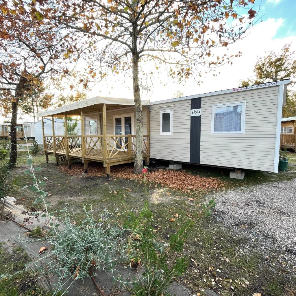 une petite maison avec une véranda et un arbre dans l'établissement Mobilhome neuf La Dolce Vita, à Claouey