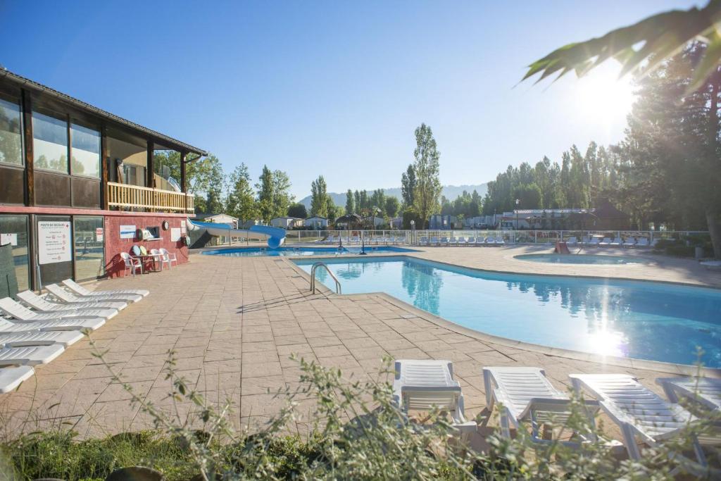 une piscine avec des chaises longues à côté d'un bâtiment dans l'établissement Les bords du Rhône, à Condrieu