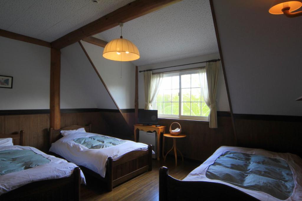 une chambre avec deux lits et une fenêtre dans l'établissement Lodge Clubman, à Hachimantai