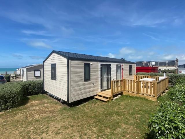 une petite maison dans une cour avec une terrasse dans l'établissement Chalet Bord de Mer, à Gouville-sur-Mer