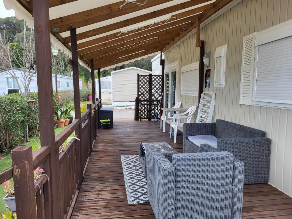 une terrasse couverte avec des chaises en osier et une terrasse en bois dans l'établissement Azur 49, à Fréjus