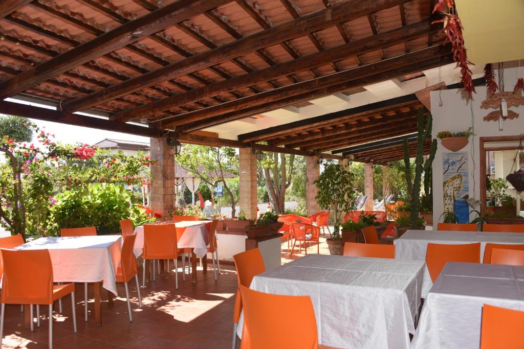 un restaurant avec des tables blanches et des chaises orange dans l'établissement Hotel Cristina, à Diamante