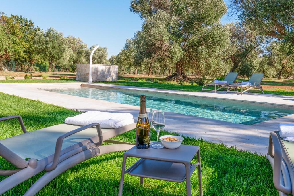- une bouteille de vin sur une table à côté de la piscine dans l'établissement Trullo Brenda By Raro Villas, à San Michele Salentino