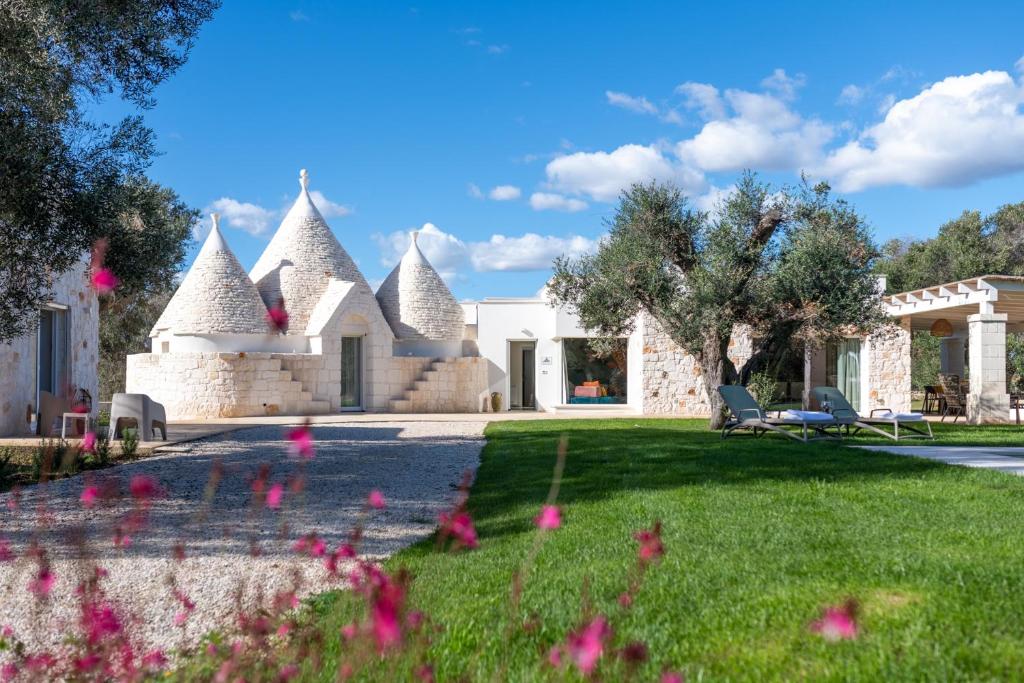 une maison avec un jardin orné de fleurs roses dans l'établissement Trullo Brenda By Raro Villas, à San Michele Salentino
