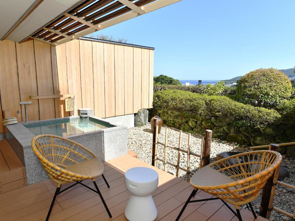 un patio avec deux chaises et une piscine dans l'établissement Seizan Yamato, à Itō