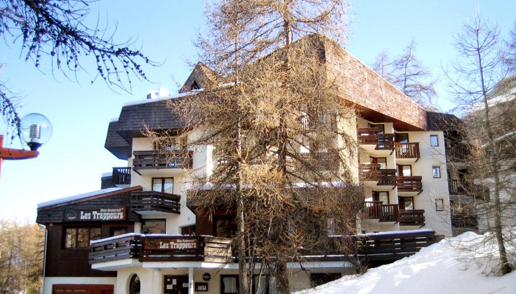 un bâtiment en hiver avec de la neige au sol dans l'établissement Hôtel Les Trappeurs, aux Orres