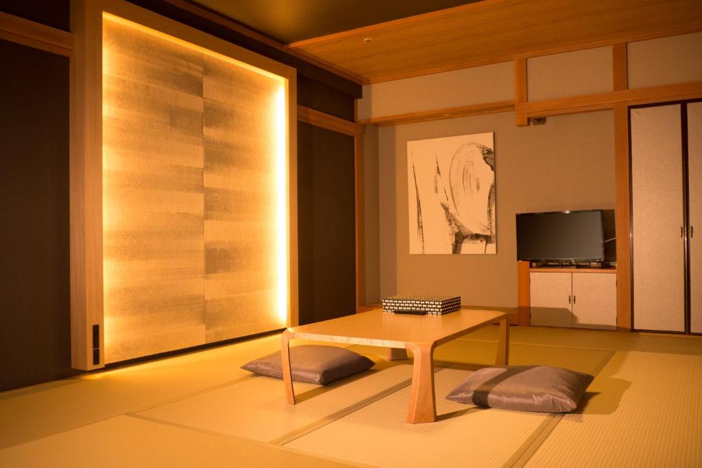 un salon avec une table et une télévision dans l'établissement Ito Kowakien, à Itō