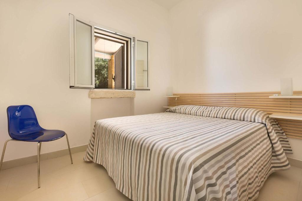 une chambre avec un lit et une chaise bleue dans l'établissement Perla Bianca by Perle di Puglia, à Torre San Giovanni 38 autres photos
