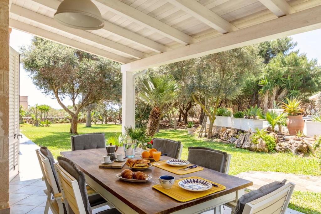 une table et des chaises en bois sur une terrasse dans l'établissement Villa Le Pigne, à Favignana
