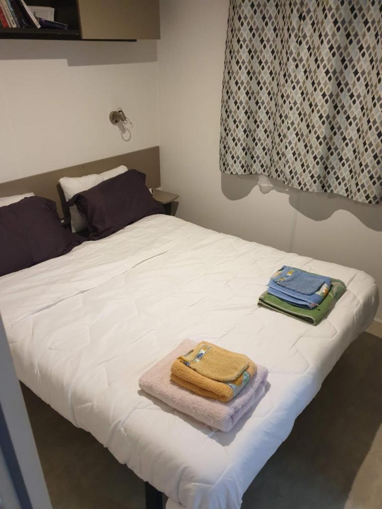 - un lit avec 2 serviettes assises au-dessus dans l'établissement Mobile home 6 personnes, à Sainte-Reine-de-Bretagne