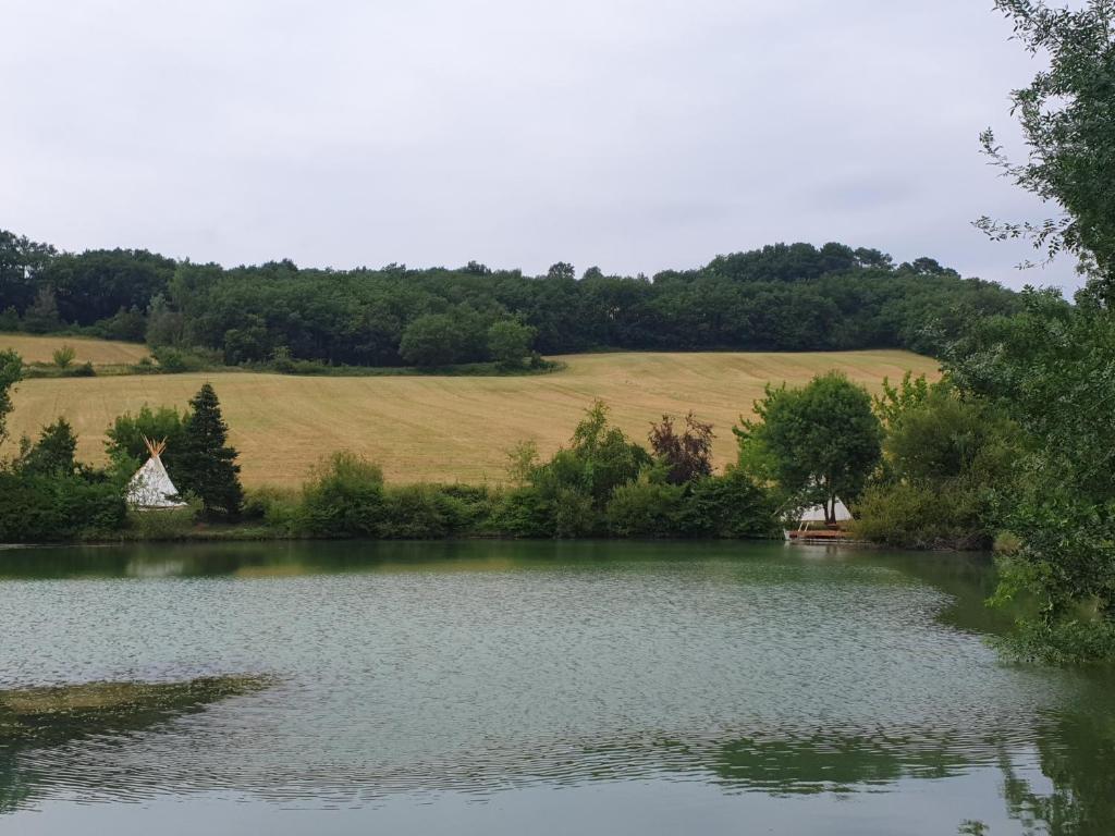 une vue sur un lac avec une ferme en arrière-plan dans l'établissement tipi des apaches, à Moulayrès