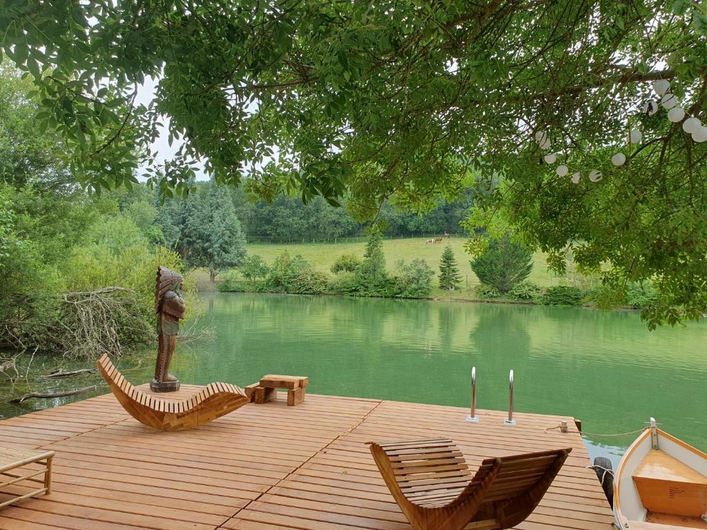 une terrasse en bois avec deux chaises et une statue sur un lac dans l'établissement tipi des apaches, à Moulayrès