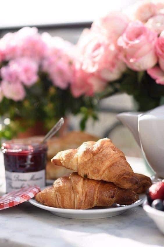 une assiette de pâtisseries sur une table avec des roses roses dans l'établissement Hotel Aria di Mare, à Marina di Ragusa
