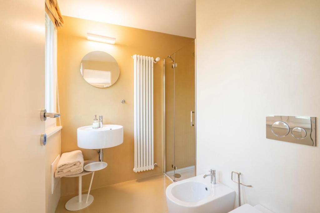 une salle de bain avec un lavabo, des toilettes et un miroir dans l'établissement Villa dei Lauri - villa vista lago con piscina, à Salò