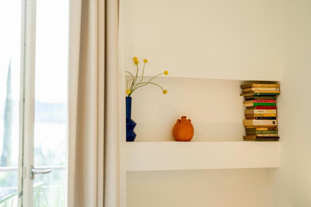 une étagère avec des livres et un vase à côté d'une fenêtre dans l'établissement Villa dei Lauri - villa vista lago con piscina, à Salò