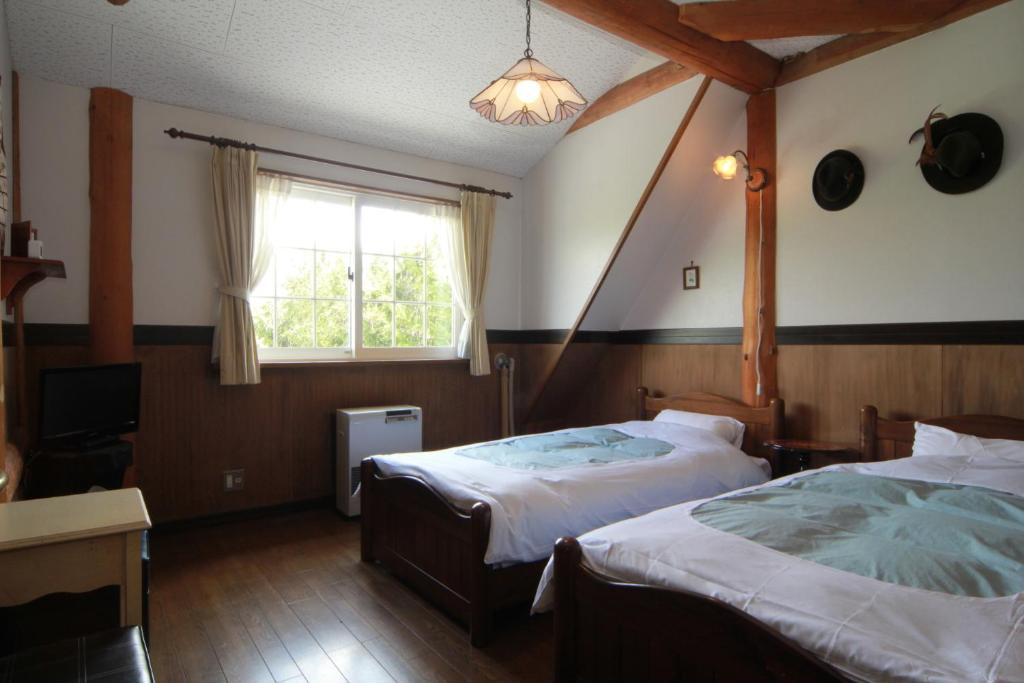 une chambre avec deux lits et une fenêtre dans l'établissement Lodge Clubman, à Hachimantai