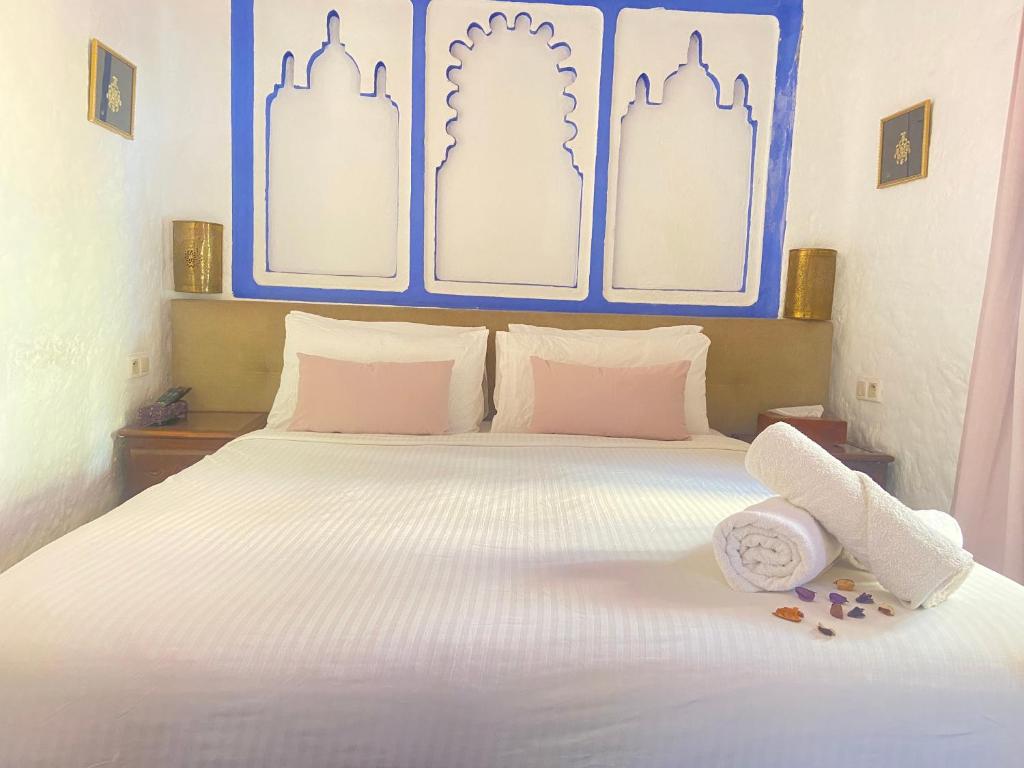 - une chambre avec un lit blanc et une serviette dans l'établissement Riad Gharnata, à Chefchaouen