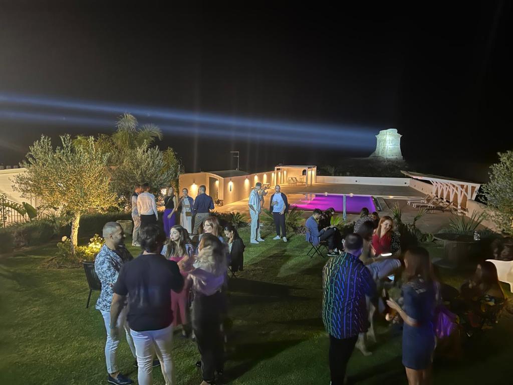 Un groupe de personnes debout dans l'herbe la nuit dans l'établissement Villa Aries - Rural Chic Experience, à Gela