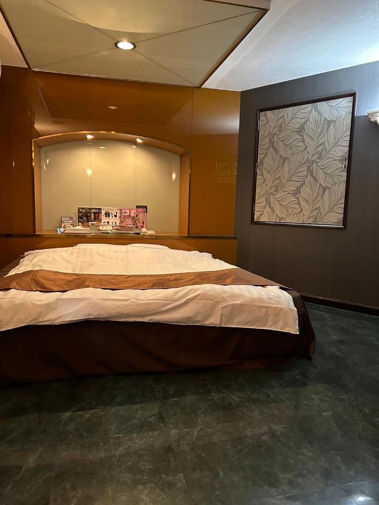 une chambre avec un grand lit dans une pièce dans l'établissement おとぼけビーバーケセラセラ寝屋川, à Neyagawa