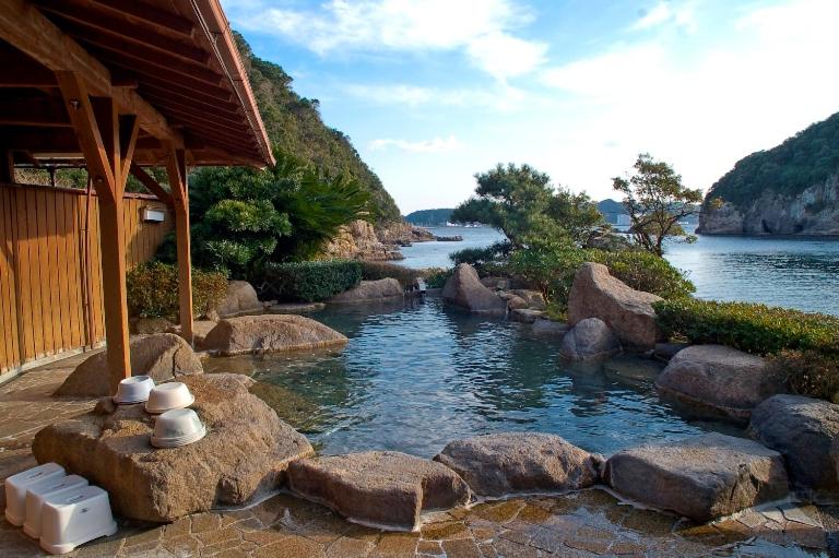 une rivière avec des rochers devant un bâtiment dans l'établissement Hotel Nagisaya, à Katsuura
