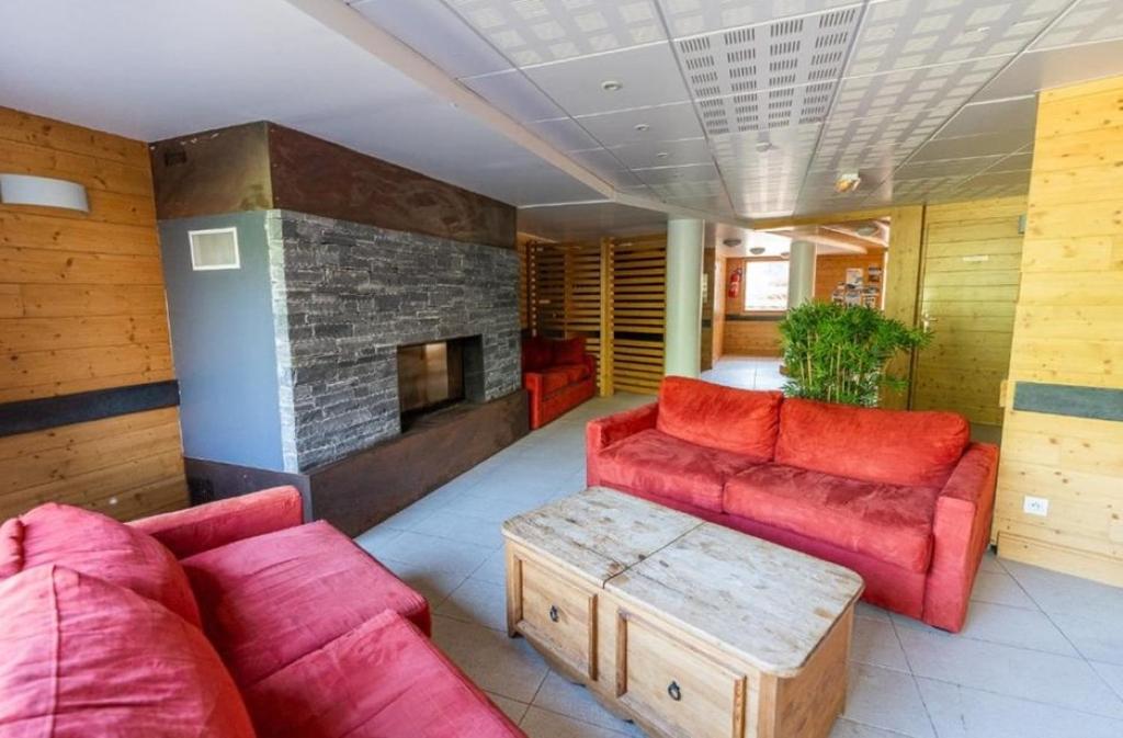 - un salon avec des canapés rouges et une cheminée dans l'établissement APT T2 4 COUCHAGES dans RES. 4 * - BALCONS des AIRELLES (1800) coeur de station, aux Orres