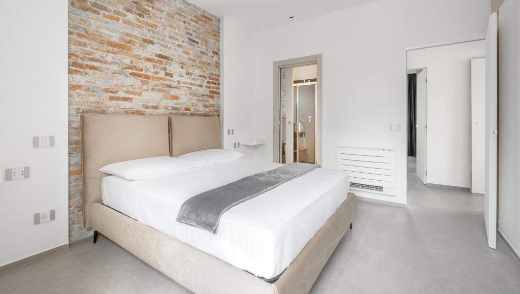 une chambre avec un grand lit et un mur de briques dans l'établissement Respiro Greco, à Syracuse