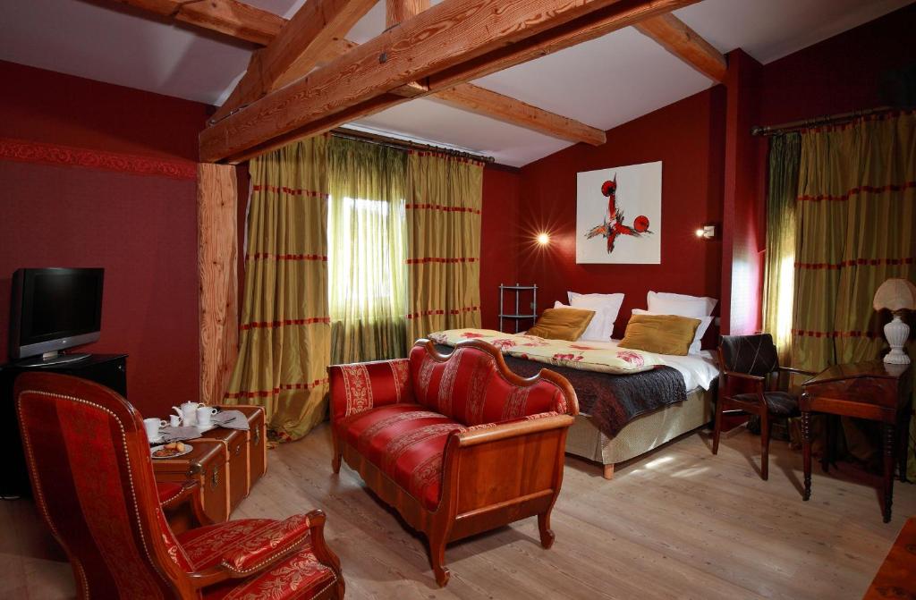 une chambre avec un lit, un canapé et une chaise dans l'établissement Hôtel Le Manoir des Montagnes, aux Rousses