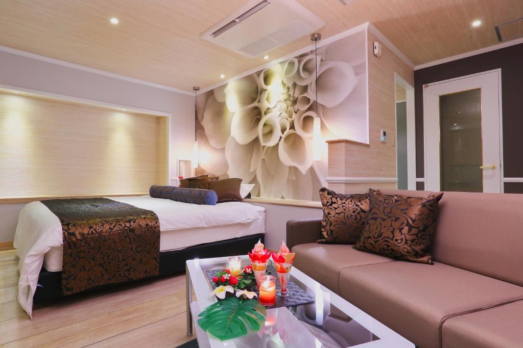 une chambre d'hôtel avec un lit et un canapé dans l'établissement HOTEL A La Mode -アラモード-, à Utazu
