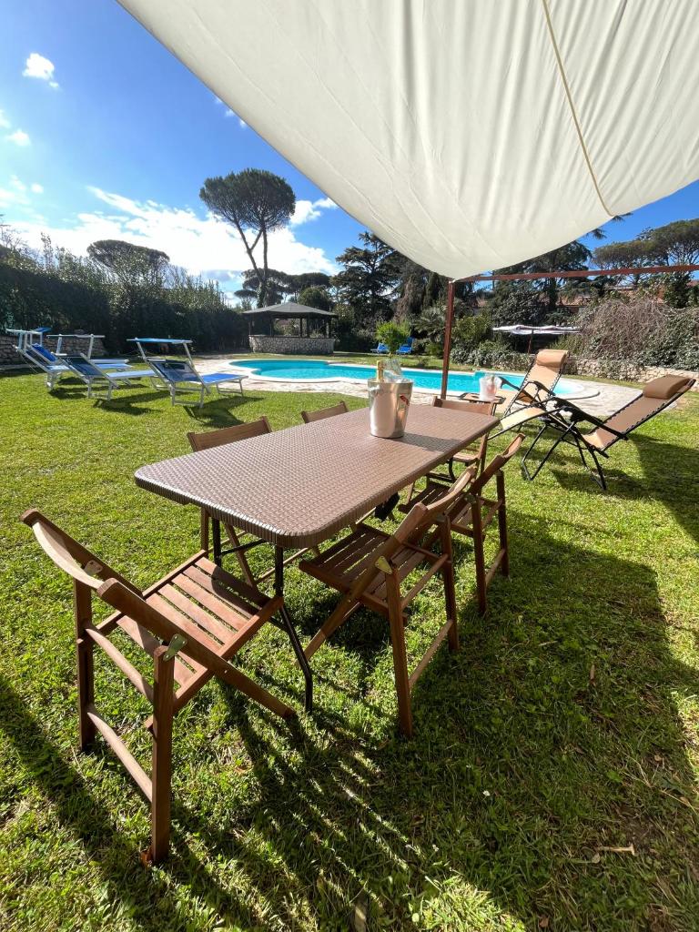 - une table de pique-nique avec 2 chaises et un parasol blanc dans l'établissement Villa Roma Open Space - Location per eventi 2 piscine riscaldate -, à Rome