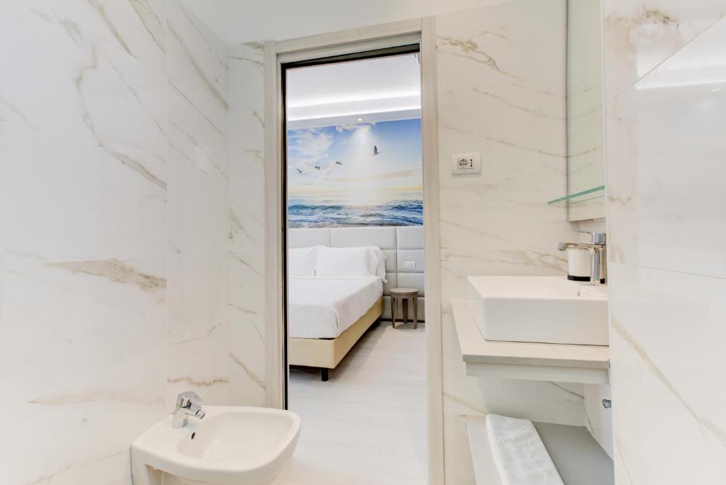 - une salle de bains blanche pourvue d'un lavabo et d'un lit dans l'établissement Hotel Sympathy, à Rimini