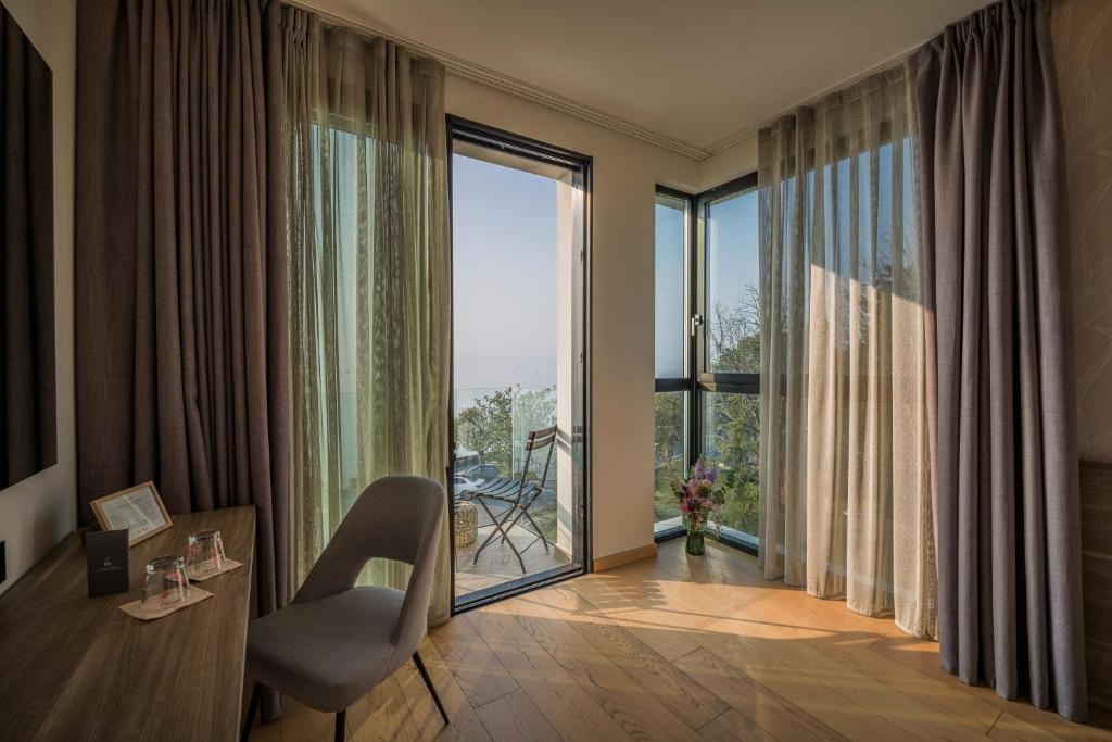 Cette chambre comprend une table, une chaise et une grande fenêtre. dans l'établissement Hotel Vinci, à Sirmione