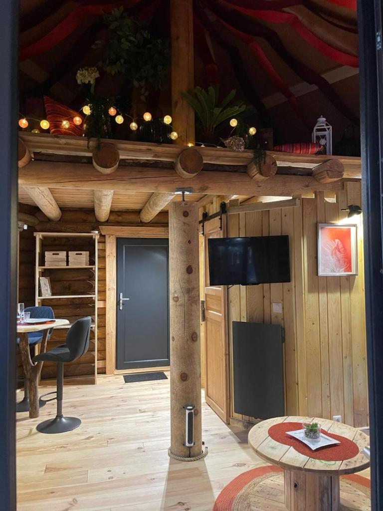 Ce chalet en bois dispose d'une table et d'une télévision. dans l'établissement LA YOURTE DU RANDONNEUR, à Rimbach-près-Masevaux