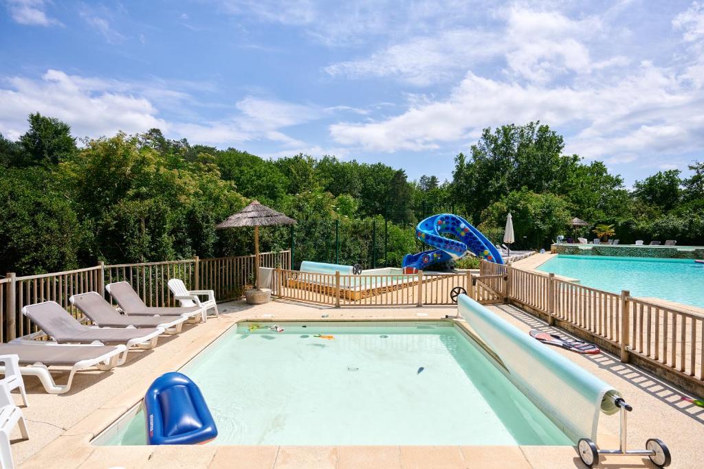 une piscine avec des chaises longues et une piscine dans l'établissement Glamping Les Eyzies, à Carmensac 37 autres photos