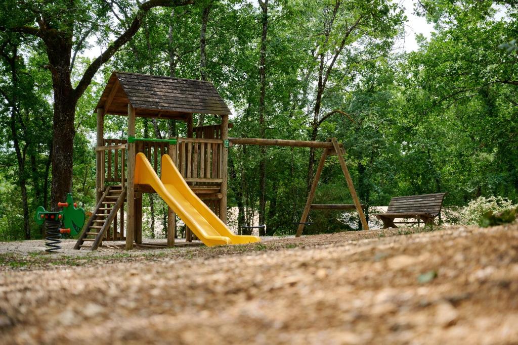 une aire de jeux en bois avec toboggan et banc dans l'établissement Glamping Les Eyzies, à Carmensac