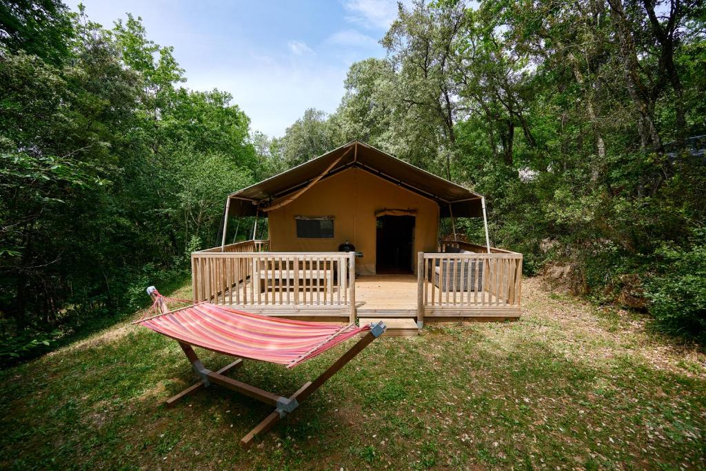 une petite maison avec un hamac en face de celle-ci dans l'établissement Glamping Les Eyzies, à Carmensac