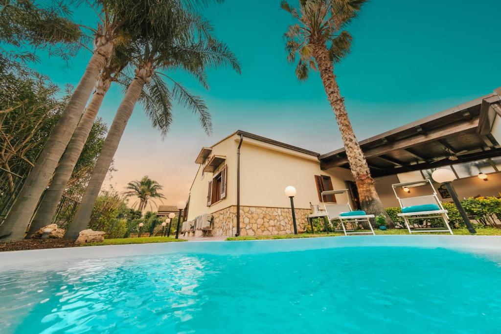 une maison avec des palmiers et une piscine dans l'établissement Villa Seaside, à Campofelice di Roccella