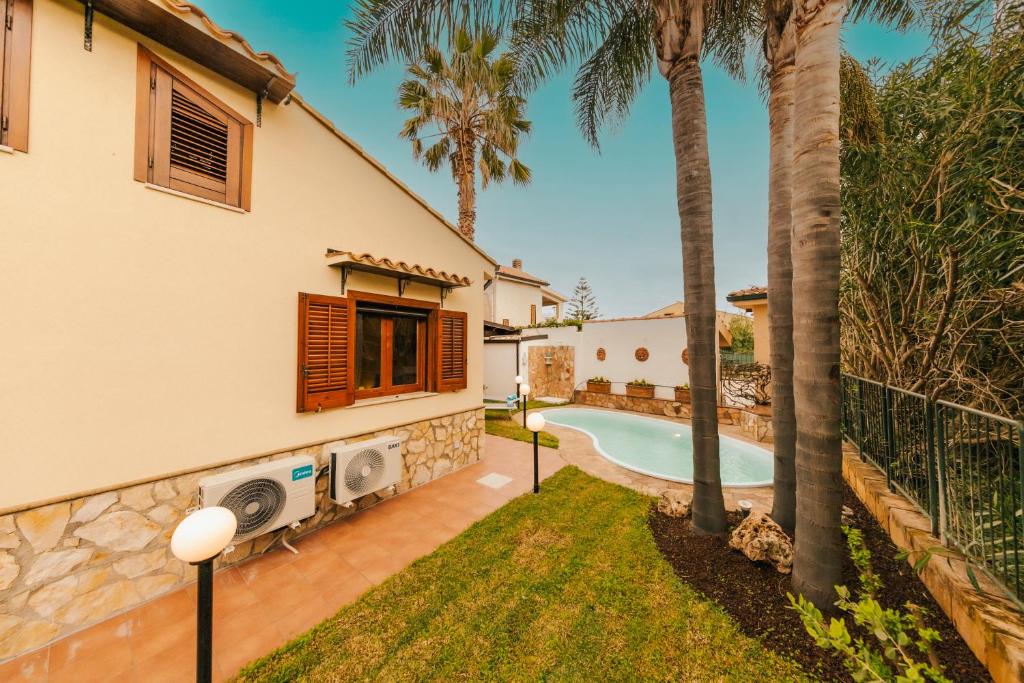 une villa avec piscine et palmiers dans l'établissement Villa Seaside, à Campofelice di Roccella