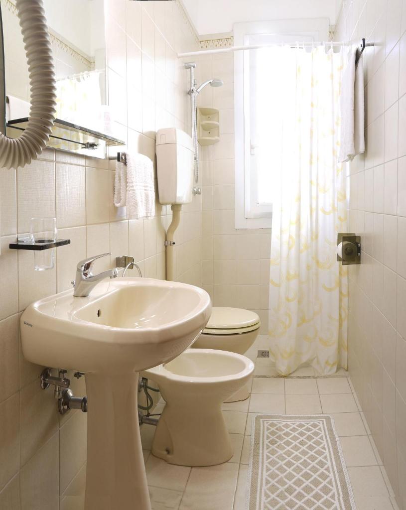 une salle de bain blanche avec un lavabo et des toilettes dans l'établissement Hotel Bellaria, à Lido di Jesolo