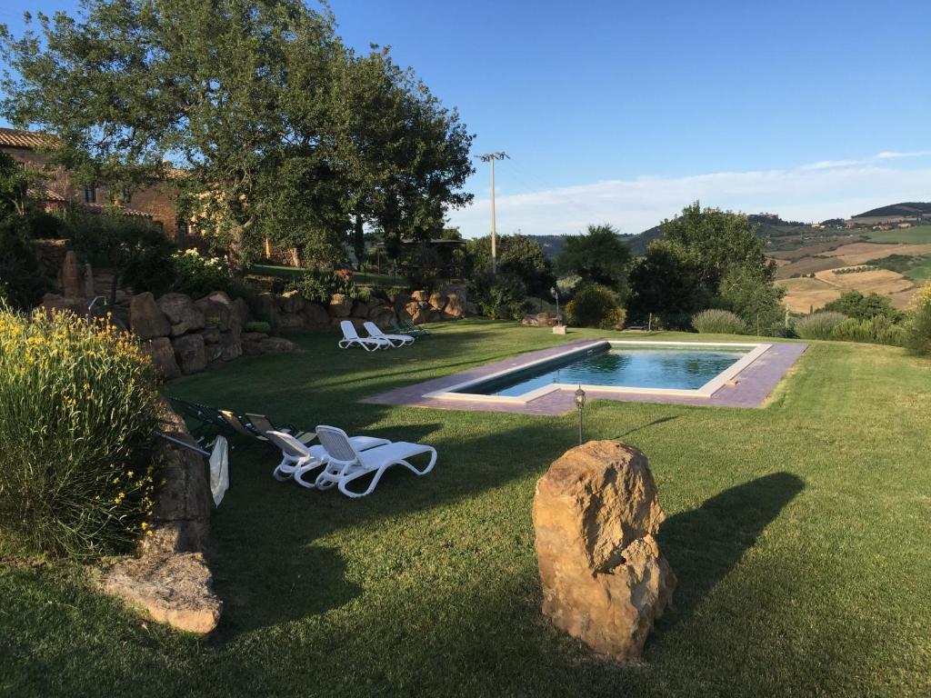 une cour avec deux chaises et une piscine dans l'établissement Villa Fonte all'Oppio con area piscina recintata, à Pienza