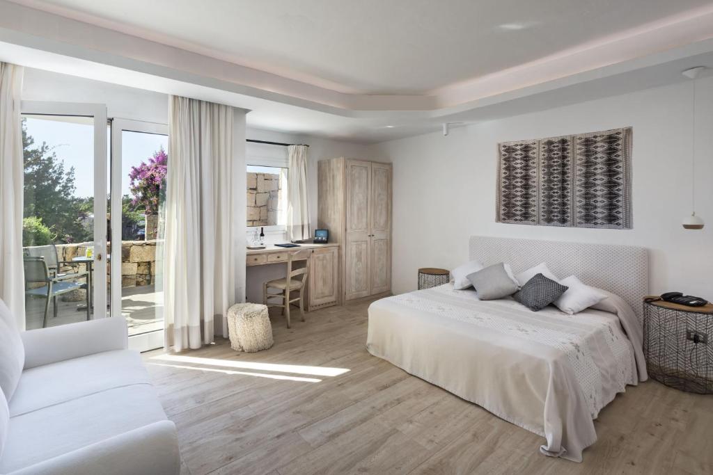 une chambre blanche avec un lit et un bureau dans l'établissement Hotel Grand Relais Dei Nuraghi, à Baja Sardinia 84 autres photos